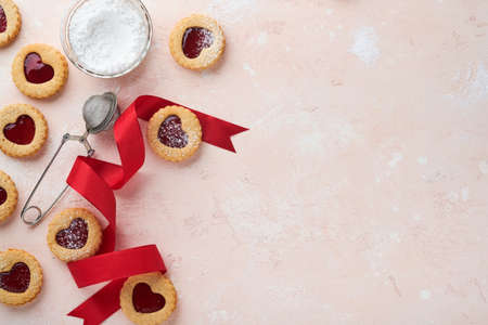 Traditional Linzer cookie with strawberry jam and powder sugar on pink beautiful background. top...