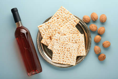 Passover celebration concept. Matzah, red kosher and walnut. Traditional ritual Jewish bread on blue...