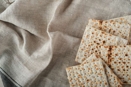 Passover celebration concept. Matzah, red kosher and walnut. Traditional ritual Jewish bread on sand color old concrete background. Passover food. Pesach Jewish holiday.の写真素材