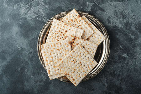 Passover celebration concept. Matzah, red kosher and walnut. Traditional ritual Jewish bread on old dark gray concrete background. Passover food. Pesach Jewish holiday.の写真素材
