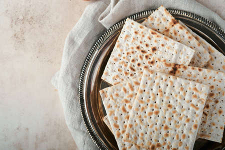 Passover celebration concept. Matzah, red kosher and walnut. Traditional ritual Jewish bread on sand...
