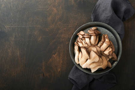 Fresh oyster mushrooms. Iron old bowl of delicious organic oyster mushrooms on old wooden background, top view with space for text.の写真素材