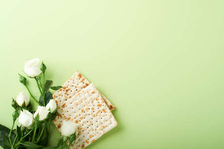 Passover celebration concept. Matzah, red kosher wine, walnut and spring beautiful rose flowers. Traditional ritual Jewish bread on light green background. Passover food. Pesach Jewish holiday.の写真素材