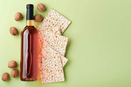 Passover celebration concept. Matzah, red kosher wine and walnut. Traditional ritual Jewish bread on light green background. Passover food. Pesach Jewish holiday.の写真素材