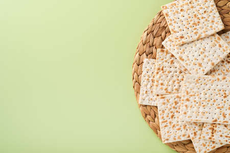 Passover celebration concept. Matzah, red kosher and walnut. Traditional ritual Jewish bread on light green monochrome background. Spring. Passover food. Pesach Jewish holiday.の写真素材