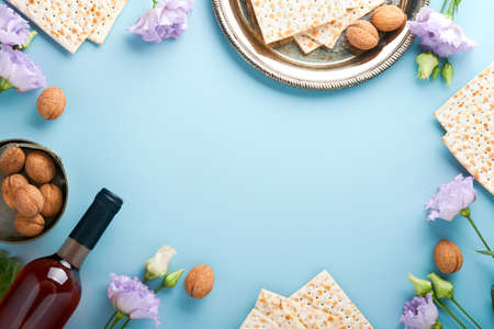 Pesach Jewish holiday. Passover celebration concept. Matzah, red kosher wine and walnut. Traditional ritual Jewish bread on light blue background. Passover food.の写真素材