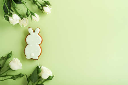 Happy Easter. Postcard with Easter cookies or gingerbread and beautiful flowers on light green background. Top view with space for your greetings.の写真素材