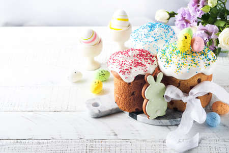 Traditional Easter sweet bread or cakes with white icing and sugar decor and quail eggs over white...