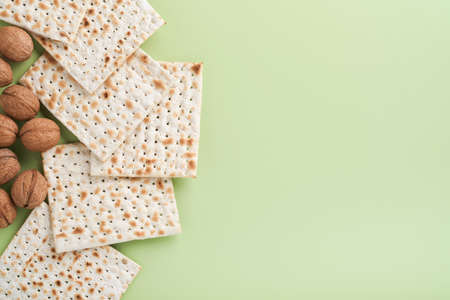 Passover celebration concept. Matzah, red kosher and walnut. Traditional ritual Jewish bread on light green monochrome background. Spring. Passover food. Pesach Jewish holiday.の写真素材