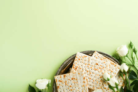 Passover celebration concept. Matzah, red kosher wine, walnut and spring beautiful rose flowers. Traditional ritual Jewish bread on light green background. Passover food. Pesach Jewish holiday.の写真素材