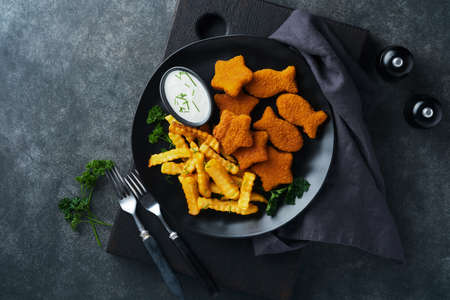 Fish Chips british fast food. Fish Sticks with french fries set on black plate on black table...
