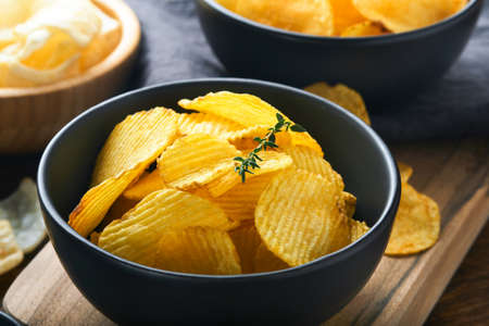 Potato corrugated chips. fast food. Crispy potato chips ceramic black bowl with sour cream sauce and...
