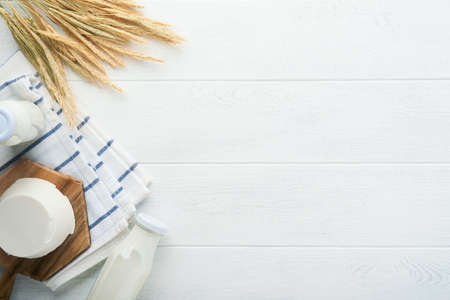 Shavuot jewish holiday celebration. Milk and cheese, ripe wheat and fruits, cream on white wooden background. Dairy products over white wooden background. Shavuot concept. top view. Mock up.の写真素材