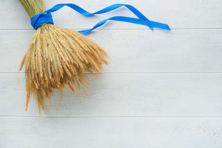 Shavuot jewish holiday celebration. Bouquet of golden ripe wheat with a blue ribbon. White wood...