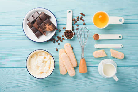 Tiramisu dessert. Ingredients for making dessert tiramisu. Cooking Italian food dessert Tiramisu with all necessary ingredients cocoa, coffee, mascarpone cheese on turquoise wooden background Top viewの写真素材