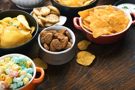 Unhealthy foods or snacks. All classic potato snacks with peanuts, popcorn and onion rings and...