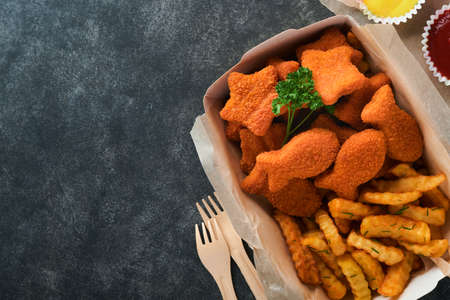 Fish and Chips british fast food. Fish Sticks with french fries set on takeaway paper plate on dark old concrete background. Traditional British authentic street food or takeaway food. Mock up.の写真素材