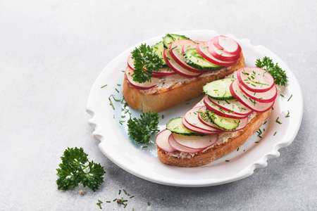 Toast with cheese and radish. Sandwiches with cottage cheese, radish, cucumber and green onions on gray concrete background. Healthy spring sandwiches. Traditional Scandinavian toast. top view.の写真素材