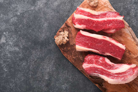 Steak beef. Raw steak New York with rosemary and spices on a piece of parchment paper on old dark...