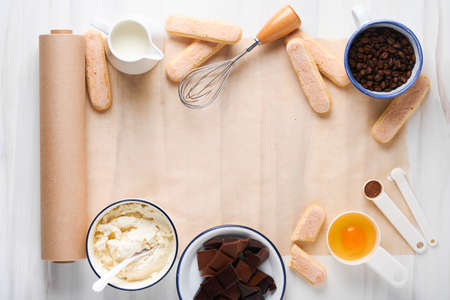 Tiramisu dessert. Ingredients for making dessert tiramisu. Cooking Italian food dessert Tiramisu with all necessary ingredients cocoa, coffee, mascarpone cheese on white stone background. Mock up.の写真素材