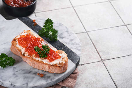 Red caviar sandwiches. Salmon red caviar in bowl and sandwiches on marble plate on old gray cracked tile table background. top view. copyspace.の写真素材