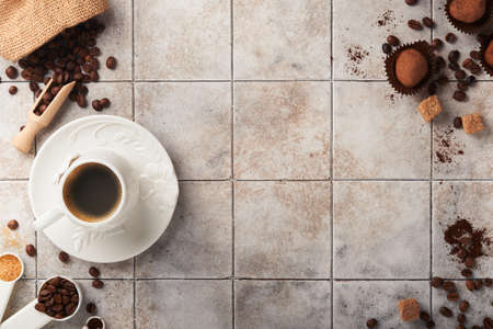 coffee background. Measuring spoons with ground coffee, beans, cup and sweet chocolate truffles on old tile cracked table background. food background. Top view with space for your textの写真素材