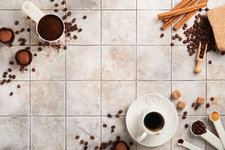 coffee background. Measuring spoons with ground coffee, beans, cup and sweet chocolate truffles on old tile cracked table background. food background. Top view with space for your textの写真素材
