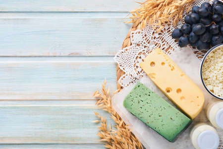 Shavuot jewish holiday celebration. Milk and cheese, ripe wheat and fruits, blue wooden background. Dairy products over blue wooden background. Shavuot concept. top view. Mock up.の写真素材