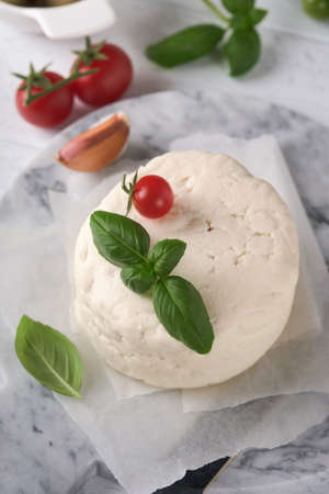 Ricotta cheese. Homemade Ricotta cheese with basil, garlic, tomatoes and green olives on parchment...