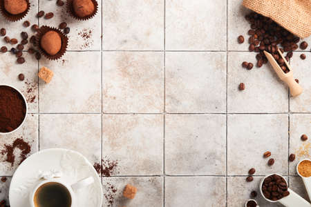 coffee background. Measuring spoons with ground coffee, beans, cup and sweet chocolate truffles on...