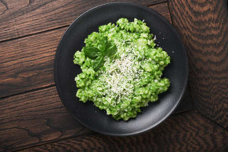 Italian risotto. Delicious risotto with pesto sauce or wild garlic pesto, basil, parmesan cheese and glass of white wine on old wooden table background. Italian dinner. Top view with copy space.の写真素材
