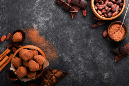 Chocolate truffles with cocoa powder in wooden dish on old dark concrete table background. Tasty...