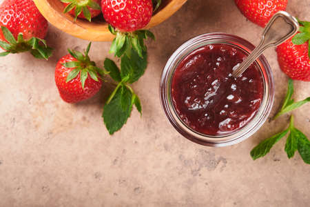 Strawberry Jam. Strawberry jam in glass jar with fresh berries plate on an old cracked tile table background, closeup. Homemade strawberry fruity jam. Top view with copy space.の写真素材