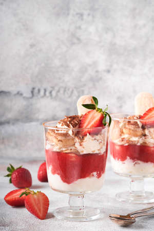 Strawberry tiramisu. Traditional Italian dessert tiramisu in glass with fresh strawberry and mint leaves on old gray concrete background table background. copyspace. food background.の写真素材