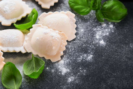 Ravioli Italian food. Tasty homemade with flour, tomatoes, eggs and greens basil on dark background....