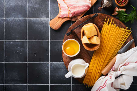 Ingredients for Pasta Carbonara. Traidtional Italian Pasta Carbonara Ingredients bacon, spaghetti, parmesan and egg yolk, garlic. Black old tile table background. top view. copy spaceの写真素材