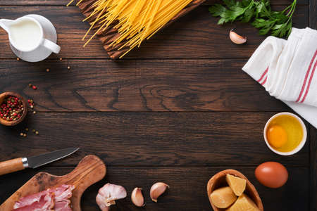 Ingredients for Pasta Carbonara. Traidtional Italian Pasta Carbonara Ingredients bacon, spaghetti, parmesan and egg yolk, garlic. Dark wooden old table background. top view. copy spaceの写真素材