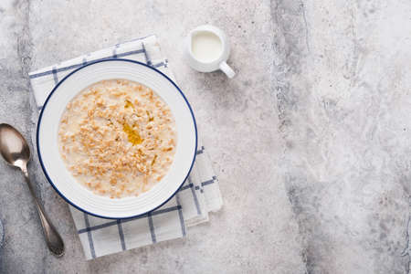 Oatmeal. Bowl of oatmeal porridge with strawberry, almond and milk on vintage light gray teal table....