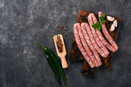 Raw sausages. Bratwurst or sausages with ingredients on cutting board with spices on a stone background with copy space. food cooking background. top view.の写真素材