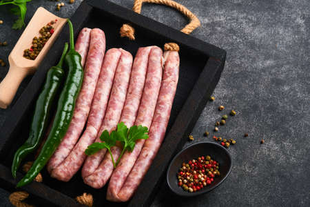 Raw sausages. Bratwurst or sausages with ingredients on cutting board with spices on a stone background with copy space. food cooking background. top view.の写真素材