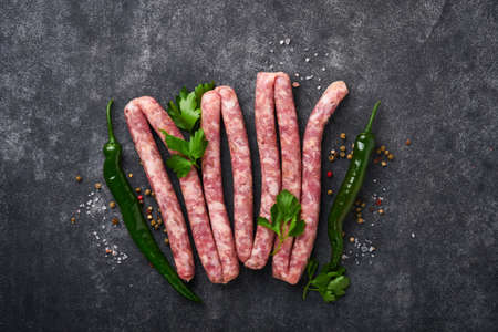 Raw sausages. Bratwurst or sausages with ingredients on cutting board with spices on a stone background with copy space. food cooking background. top view.の写真素材