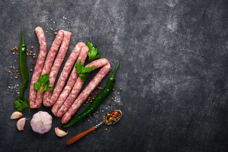 Raw sausages. Bratwurst or sausages with ingredients on cutting board with spices on a stone background with copy space. food cooking background. top view.の写真素材