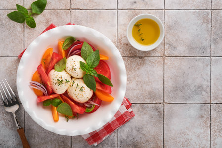 Caprese salad. Italian caprese salad with sliced tomatoes, mozzarella cheese, basil, olive oil in white plate over white background. Delicious Italian food. top view. rustic style.の写真素材