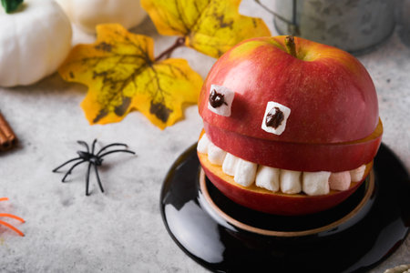 Spooky green kiwi monsters for Halloween. Healthy Fruit Halloween Treats. Halloween party kiwi, strawberry, apple and marshmallow monster on gray stone or concrete table background. selective focus.の写真素材