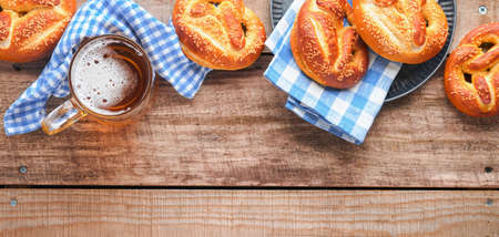 Bavarian pretzels and glass of lager beer. Oktoberfest food menu, traditional salted pretzels over old wooden background. Top view with space for text. Oktoberfest themeの写真素材
