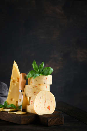 Stack of cheese with tomatoes and seasoning and Swiss cheese on with basil and knife on serving...