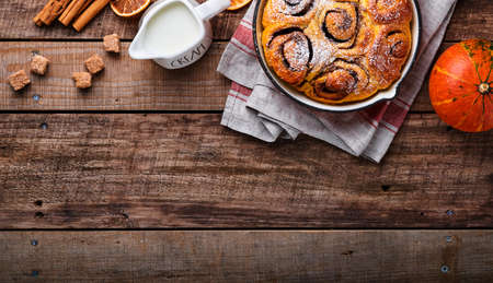 Cinnabon cinnamon rolls buns with pumpkin, nut, caramel and sugar cream iced on rustic wooden background table. Top view. Sweet Homemade Pastry christmas baking. Kanelbule - swedish dessert.の写真素材