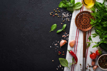 Frying pan white , black empty plate, basil leaves and spices on dark stone background. Abstract food background. Top view of dark rustic kitchen table with wooden cooking utensilsの写真素材
