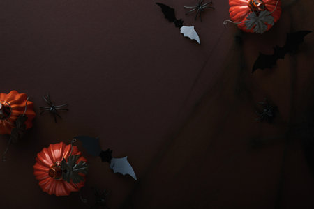 Halloween background. Flock of black bats, spider, pumpkin, skeleton and leaves for Halloween. Black paper bat silhouettes on brown or dark background. autumn decoration. Halloween concept. top view.の写真素材