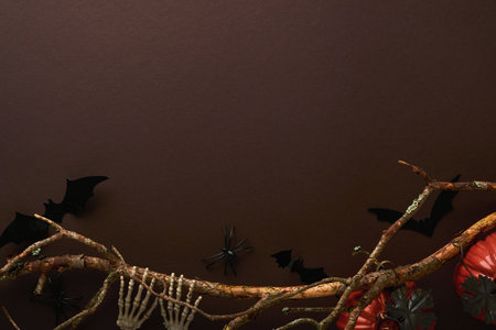 Halloween background. Flock of black bats, spider, pumpkin, skeleton and leaves for Halloween. Black paper bat silhouettes on brown or dark background. autumn decoration. Halloween concept. top view.の写真素材